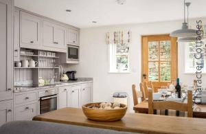 a kitchen with white cabinets and a wooden bowl on a table at Willow Vale in Snowshill