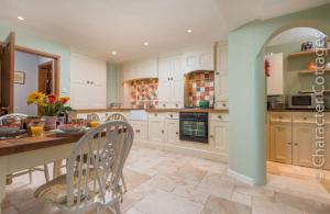 a kitchen with white cabinets and a table and chairs at Mill Stream Cottage in Lower Slaughter