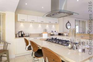 a kitchen with a counter with chairs and a stove at Honeystones in Bourton on the Water