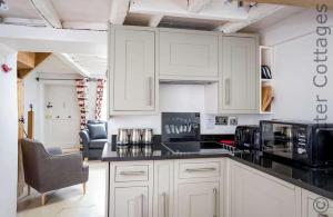 a kitchen with white cabinets and a black counter top at Dove Cottage Naunton in Naunton