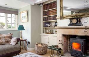 a living room with a fireplace with a mirror above it at Willow Cottage in Hampnett +22 photos