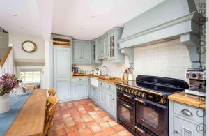 a kitchen with white cabinets and a stove top oven at Willow Cottage in Hampnett