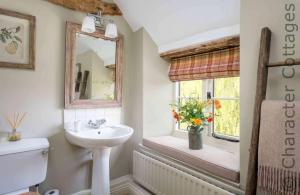 a bathroom with a sink and a window with flowers at Willow Cottage in Hampnett