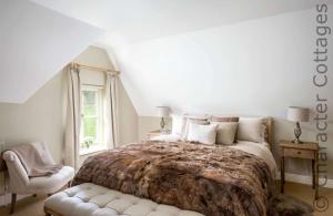 a bedroom with a large bed and a chair at Willow Cottage in Hampnett