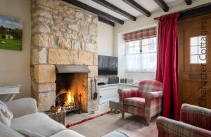a living room with a stone fireplace and red curtains at Lanes Cottage in Chipping Campden