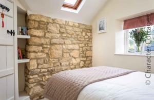 ein Schlafzimmer mit einer Steinmauer und einem Bett in der Unterkunft Lanes Cottage in Chipping Campden