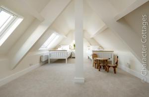 een zolderkamer met een bed en een tafel en stoelen bij Wall Cottage in Burford