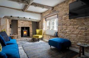 a living room with a blue couch and a stone wall at Millbank Cottage in Mickleton