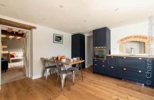 a kitchen with blue cabinets and a table with chairs at The Creamery in Nympsfield