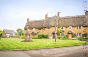 une grande maison en briques avec une cour d'herbe dans l'établissement Holly Cottage Middle Tysoe, à Middle Tysoe