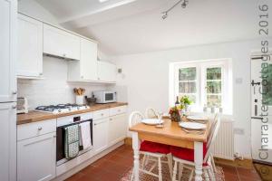 a kitchen with white cabinets and a wooden table at Primrose Cottage Blockley in Blockley