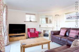 a living room with a couch and a tv at Headford Cottage in Stow on the Wold