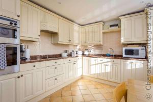 una cocina blanca con armarios y electrodomésticos blancos en Headford Cottage, en Stow on the Wold