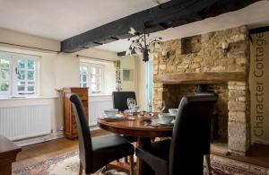 a dining room with a table and a stone fireplace at Court Hayes in Cheltenham