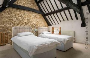 two beds in a bedroom with a stone wall at Court Hayes in Cheltenham