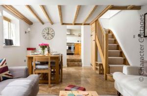 a living room with a table and a clock on the wall at Wyncliffe in Chipping Campden