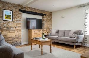 a living room with a couch and a tv at High Ridge in Idbury