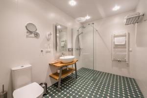 bagno bianco con lavandino e doccia di Hotel Miķelis a Uzvara