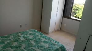 an empty bedroom with a bed and a window at Residencial Ponta das Canas in Florianópolis