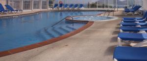une grande piscine avec des chaises bleues dans un bâtiment dans l'établissement Hotel Las Sirenas, à Viveiro