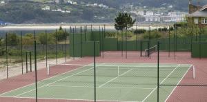 una pista de tenis con dos redes de tenis en Hotel Las Sirenas en Viveiro