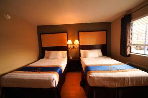 een hotelkamer met 2 bedden en een raam bij Sandals Inn in Daytona Beach