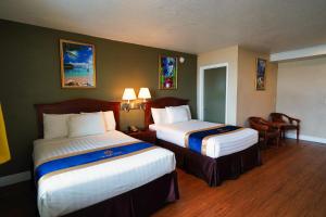 een hotelkamer met 2 bedden en een tafel en stoelen bij Sandals Inn in Daytona Beach