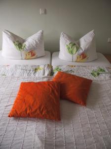 dwa łóżka z pomarańczowymi poduszkami na górze w obiekcie Gastehaus Weingut Rossler w mieście Lorch