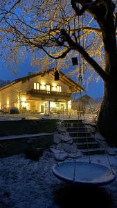 a building with a tree in the snow at night at Pure Nature Munich - Alps in Fischbachau