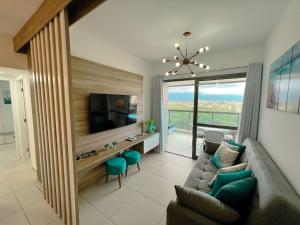 un salon avec un canapé et une télévision dans l'établissement Home 49 I Apto pé na areia e piscina aquecida em Bertioga, à Bertioga