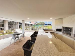 une cuisine avec un long comptoir avec des chaises et des tables dans l'établissement Home 49 I Apto pé na areia e piscina aquecida em Bertioga, à Bertioga