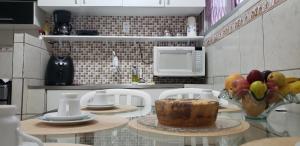 Confortável apartamento próximo à Ponta Negra في ناتال: مطبخ مع طاولة مع كعكة و صحن من الفاكهة