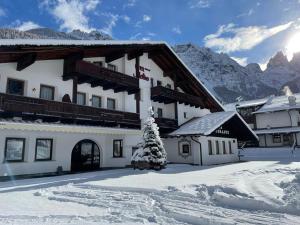 a building with a christmas tree in the snow at Hotel Molino in Falcade