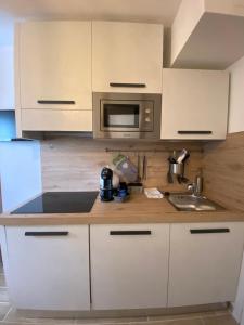 une cuisine avec des armoires blanches, un évier et un micro-ondes dans l'établissement Casa Sestriere - bilocale in centro a Sestriere, à Sestrières 9 autres photos