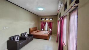1 dormitorio con 1 cama y 2 sillas en G-Rima Home Stay, en Labuan Bajo