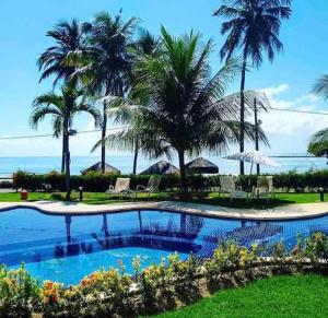 a swimming pool with palm trees in a resort at Tamandaré Holiday Flat Beira-Mar Apartamento 107 in Tamandaré