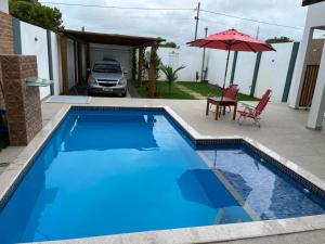 a blue swimming pool with a table and an umbrella at Casa com piscina - Prado in Prado