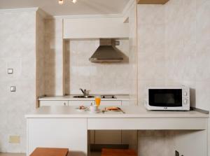 cocina blanca con microondas y fregadero en Apartamentos Portazgo, en A Coruña