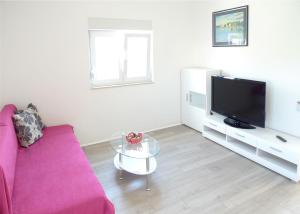a living room with a pink couch and a tv at Apartments Sunset in Olib