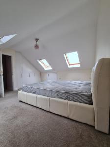 a large bed in a white room with skylights at Croydon - Compton in South Norwood