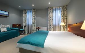 een slaapkamer met een groot bed en een blauwe bank bij Hôtel De Wimereux in Wimereux