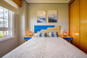 um quarto com uma cama grande e 2 janelas em San Amaro Beach 3 by TheBlueWaveApartments com em La Coruña