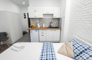 a bedroom with a bed and a kitchen with white cabinets at Apartament Estakada 2 in Częstochowa