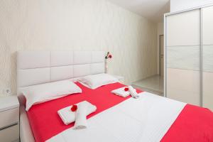 un letto bianco con asciugamani rossi e bianchi di Apartmani Kaštelančić a Podstrana