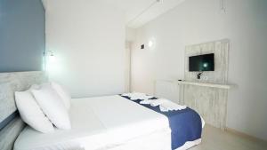 een slaapkamer met een bed met witte kussens en een televisie bij Afytos Akcay Tatil Koyu in Balıkesir