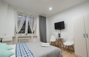 a white bedroom with a bed and a tv at Apartament Estakada in Częstochowa