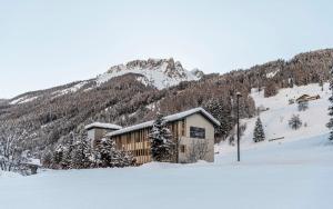 een gebouw in de sneeuw voor een berg bij LaMonte Premium Apartments by Feuerstein in Colle Isarco