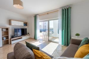 a living room with a couch and a tv at Apartamento Monarquia - T3 Quarteira in Quarteira