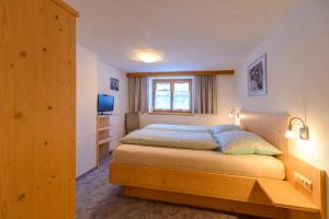 Schlafzimmer mit einem Bett, einem Fenster und einem TV in der Unterkunft Haus St. Bernard in Pettneu am Arlberg