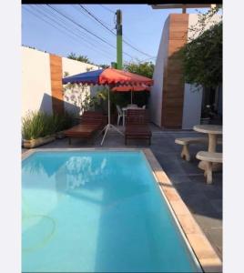 a swimming pool with a table and chairs and an umbrella at Hostel Gratidão in Itanhaém